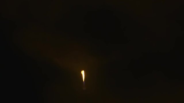 Rocket booster descends at night back to landing zone after launching a space capsule into orbit. 120 fps slow motion.