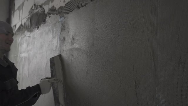 The builder levels the surface on the grid with putty and smiles