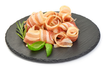 Rolled Bacon Strips on a slate shale plate, close up, isolated on a white background