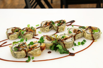 Hot fried Sushi Roll with salmon skin, chive and teriyaki. Sushi menu. Japanese food. Futomaki. Isolated on white background