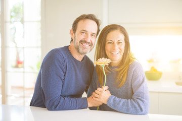 Romantic middle age couple holding flowers in love at home