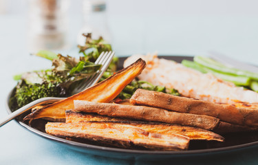 Sweet potato wedges and salmon fillet served with tenderstem broccoli and green beans
