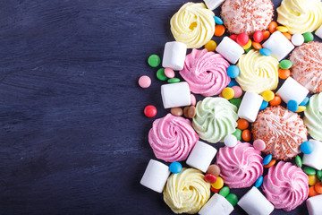 mixed multicolored candies on black wooden background.