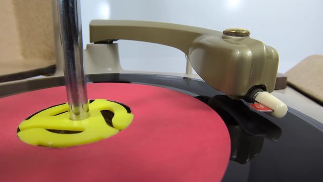 Closeup of vintage record player turntable spinning with needle on 45 speed vinyl disc.