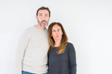 Fototapeta premium Beautiful middle age couple in love over isolated background making fish face with lips, crazy and comical gesture. Funny expression.