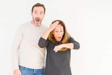 Beautiful middle age couple in love over isolated background Looking at the watch time worried, afraid of getting late