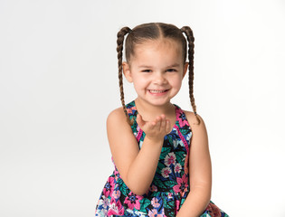 Little girl in pigtails with hand out after blowing a kiss