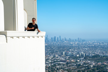 Young man sitting with a Los Angeles downtown view in the background. Amazing Hollywood.