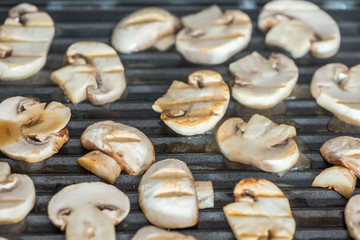 Sliced champignons mushrooms grilled on electric grill or BBQ close up view