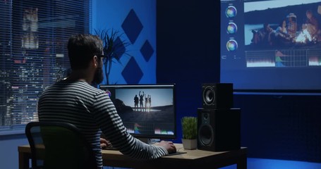 Medium shot of young man sitting back and editing video inside a room