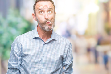 Fototapeta premium Middle age hoary senior business man over isolated background making fish face with lips, crazy and comical gesture. Funny expression.