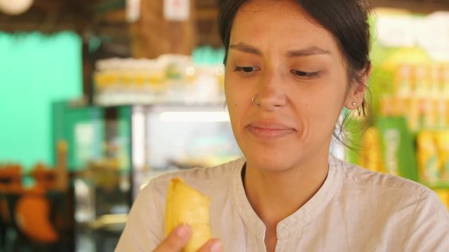 Young Mixed Race Girl Taking Piece of Ripe Durian and Enjoying the Taste of Exotic King of Fruits. 4K. Kuala Lumpur, Malaysia.
