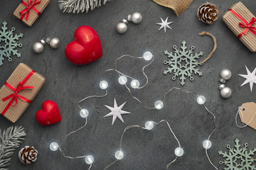 Christmas lights, red stone hearts, wrapped gifts, tags, cords and trinkets on dark