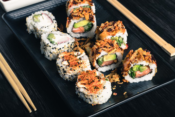 Sushi rolls with chopsticks and soy sauce on dark background