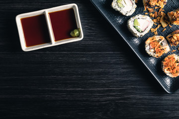 Sushi rolls with soy sauce on dark background. Space text