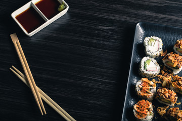 Obraz na płótnie Canvas sushi rolls with chopsticks and soy sauce on dark background. Space text