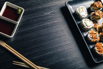 Sushi rolls with chopsticks and soy sauce on dark background. Copy space