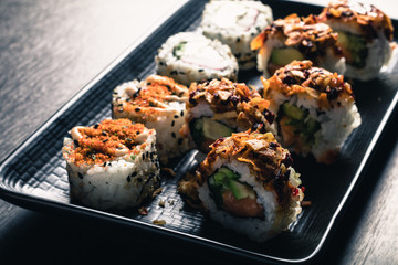 close up of sushi rolls on black tray