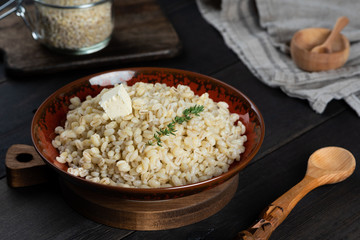 Pearl barley porridge in a plate on a black wooden background