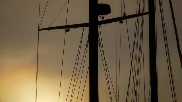 Mast and rigging of a tall sailboat silhouetted against a nice golden sunset sky
