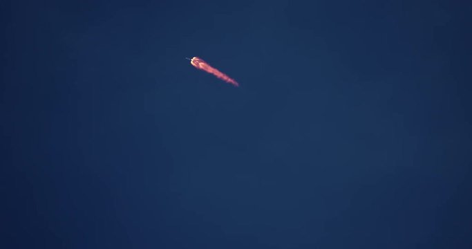 High-flying ICBM missile rocket flying into space with bright yellow exhaust flames and smoke in 4K.