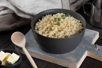 Pearl barley porridge in a plate on a black wooden background
