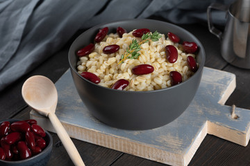 Pearl barley porridge in a plate on a black wooden background