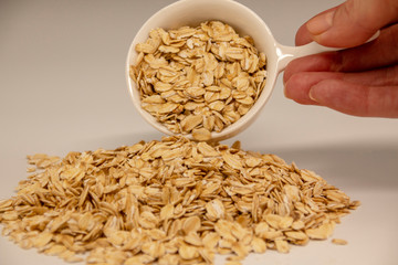 fingers hold a bowl with oatmeal, handful, on a white background