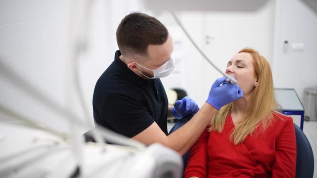 Woman patient at dentist cabinet make oral hygiene dental treatment during surgery