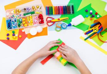 Child makes a hack box chameleon. Material for creativity on a white background.