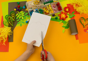 Naklejka na ściany i meble Child makes craft tree of paper. Orange background and materials for creative classes.