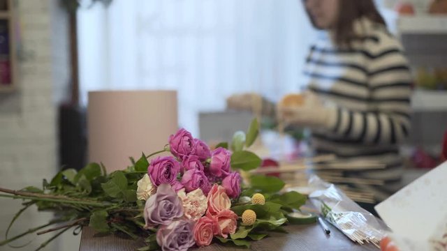 Slow shot of the bouquet in the foreground. Bouguet is very big and beautiful with purple and pink roses and many other greens.
