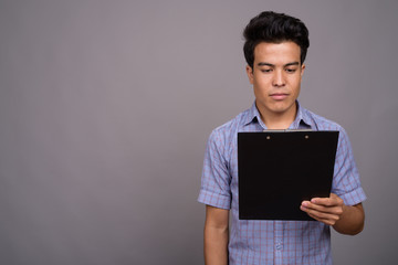 Portrait of young Asian businessman against gray background