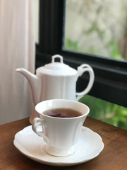 White coffee cup and teapot on wooden table