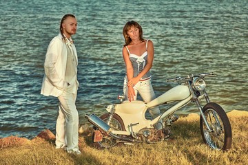 Naklejka premium Young romantic couple with vintage custom motorbike on the tropical coast background.