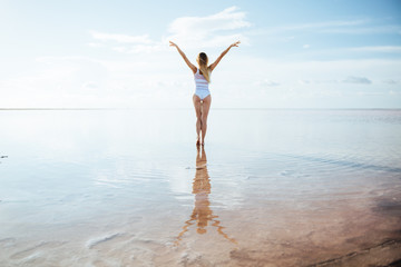 Elegant woman dancing on water. Sunset and silhouette.
