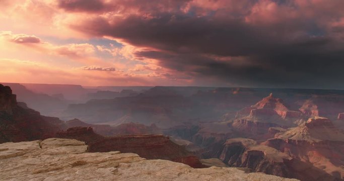 Iconic classic shot of Grand Canyon at sunset with amazing lighting, clouds, red cliffs and blue skies in 4K DCI.