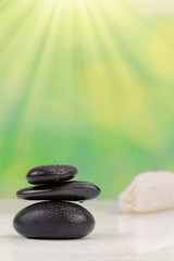 Fototapeta na wymiar Balanced zen stones with drops of water on a green bokeh background