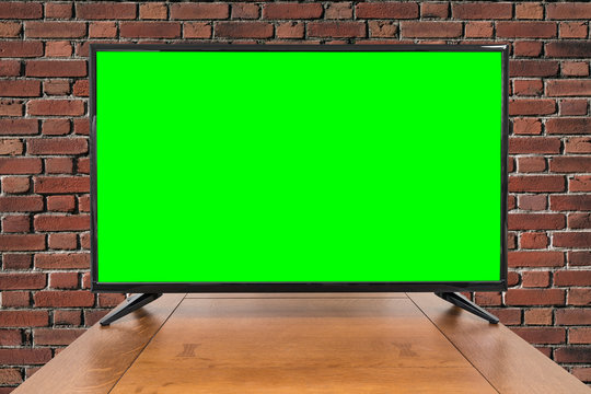 Modern television on table with brick wall and chroma key green screen. 