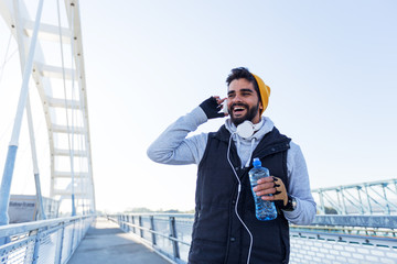 Young fitness man going on training,holding water and listening music