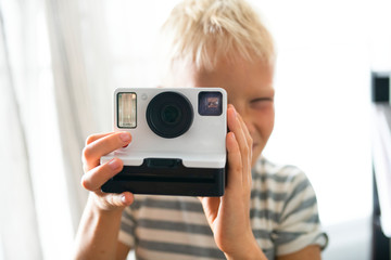 Naklejka premium Blond boy taking an instant photo
