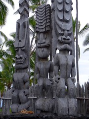 Three big wooden Tiki sculptures in the Pu'uhonua o Honaunau National Park, Big Island, Hawaii