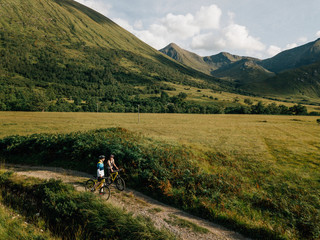 Fototapeta premium Couple cycling down a road in the Scottish Highlands