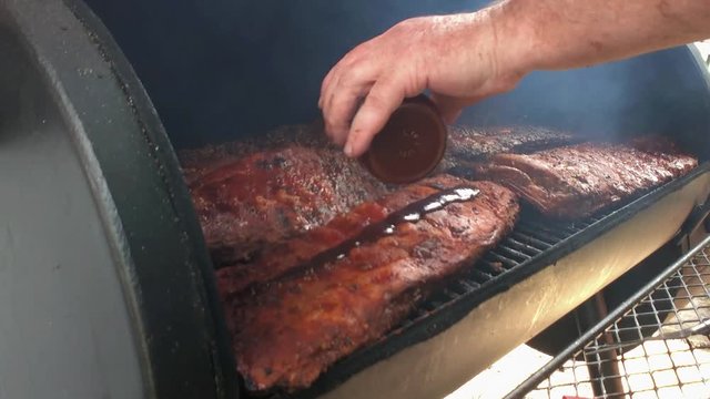 Racks of ribs having sauce applied in an off set smoker