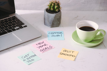 laptop with blank screen and paper stickers and cup of coffee on tabletop