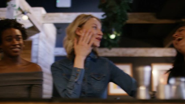 Group of young women at a bar listening to one of their friends telling a story