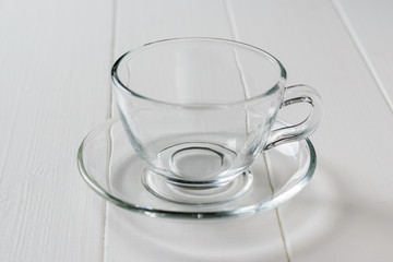 Empty glass Cup with saucer on white wooden table.