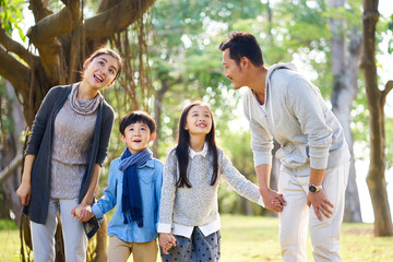 asian family with two children having fun in park