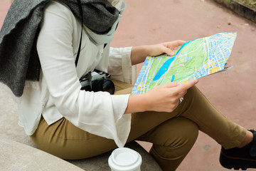 Young thoughtful tourist girl in warm clothes with map
