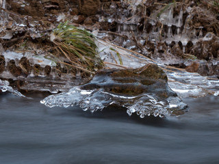 smooth motion of wild water in a river in winter with snow and ice on rocks and stones in the beautiful nature of a forest